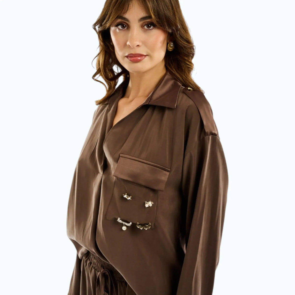 Blusa marrone in modal e raso con taschino, spille gioiello e alamari sulle spalle, indossata da modella