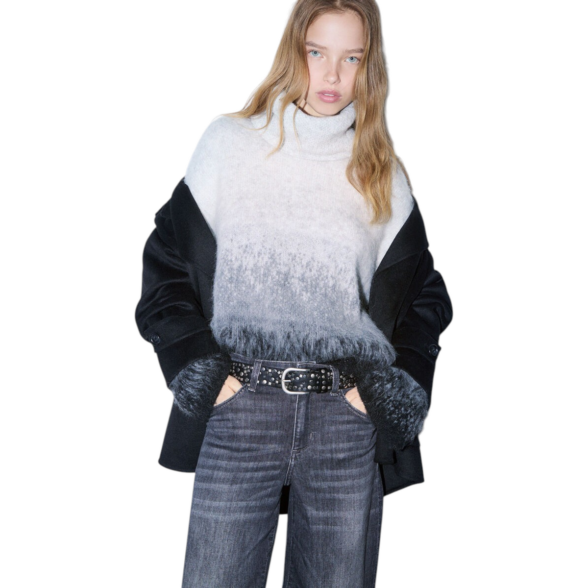Modella indossa maglione a collo alto in lana sfumata dal grigio al nero con giacca scura e jeans